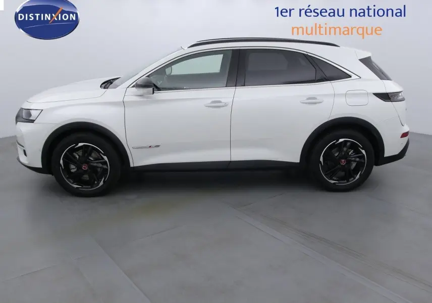 Vue latérale droite d'un DS7 Crossback E-TENSE 300CH blanc nacré métallisé avec jantes noires en intérieur studio.