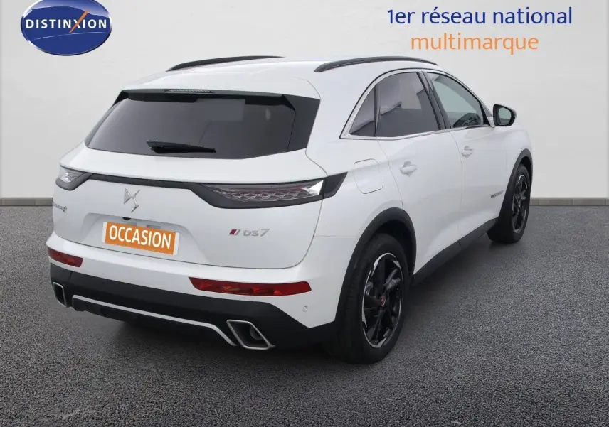 Vue 3/4 arrière droite d'un DS7 Crossback blanc nacré avec jantes noires et feux arrière effilés.