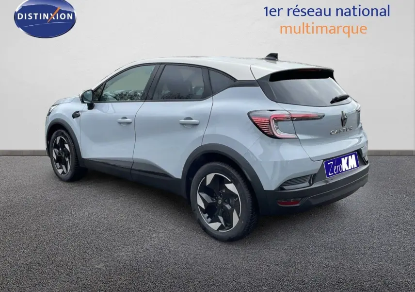 Vue 3/4 arrière droite d'un Renault Captur gris rafale métal avec toit beige, jantes noires et détails noirs contrastants.