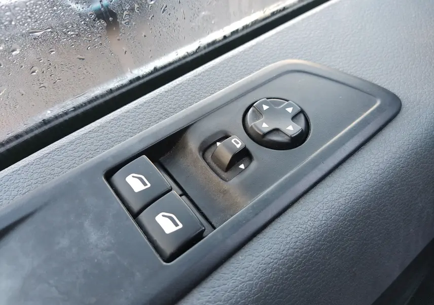 Gros plan sur les commandes de lève-vitres et réglage des rétroviseurs côté conducteur du Citroën Jumpy blanc de 2021.