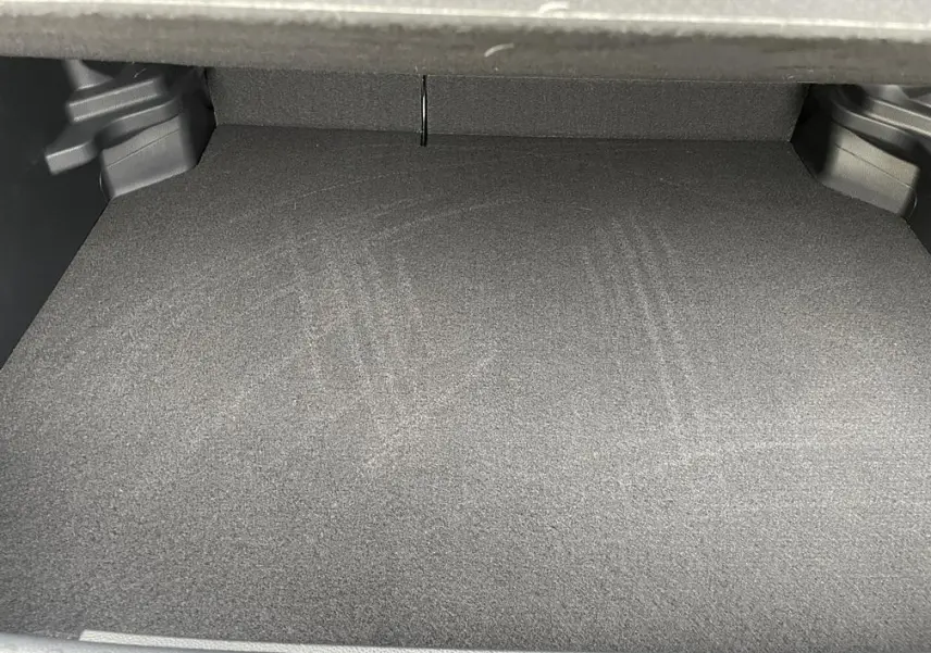 Coffre vide de la Toyota Yaris Cross 1.5 Hybrid 130h, vue intérieure, revêtement gris foncé uniforme.