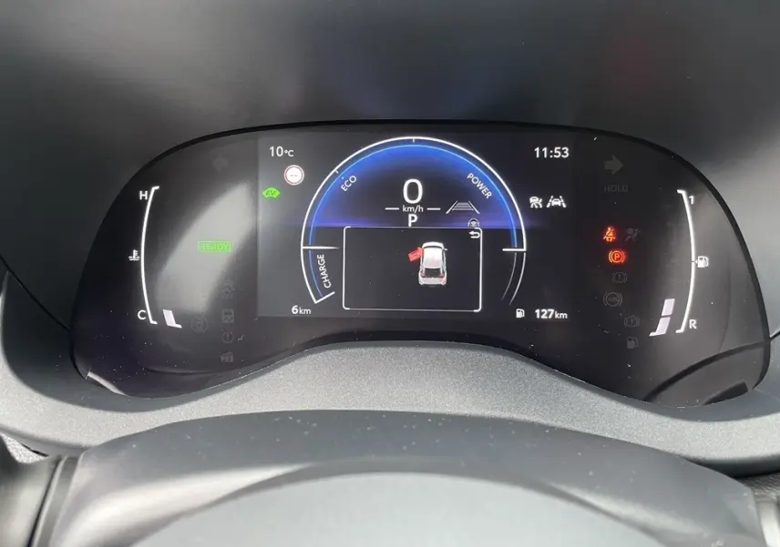 Vue rapprochée du tableau de bord numérique de la Toyota Yaris Cross 1.5 Hybrid 130h, affichage vitesse et alertes actives.