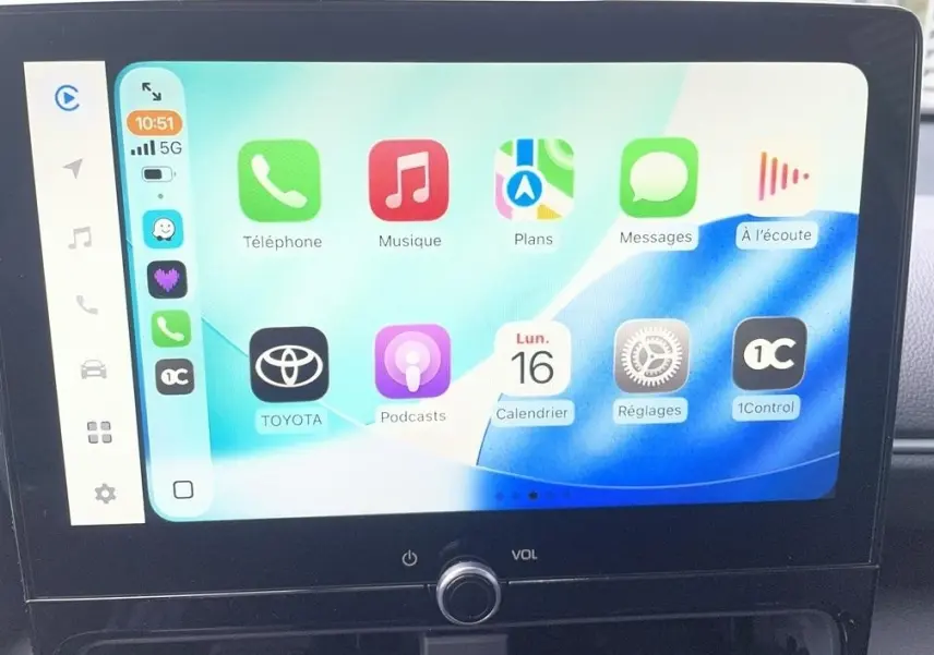 Écran tactile central affichant Apple CarPlay dans une Toyota Yaris Cross 1.5 Hybrid gris clair, vue intérieure frontale.