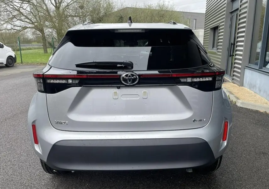 Vue arrière de la Toyota Yaris Cross gris clair 2026 avec feux arrière en bandeau et logo Toyota central.