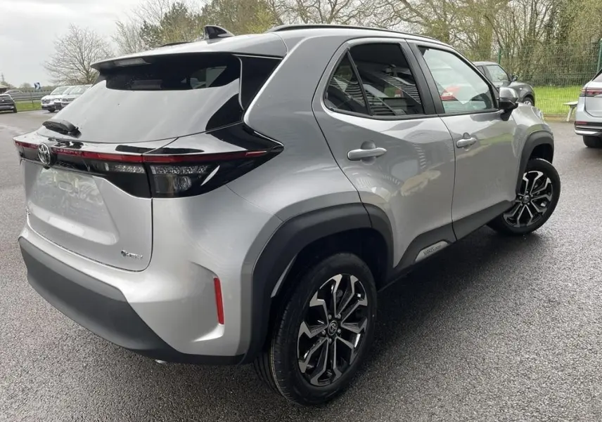 Vue 3/4 arrière droite d'une Toyota Yaris Cross gris clair avec jantes noires et toit noir contrasté.