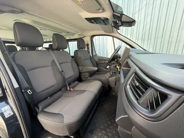 Vue intérieure côté droit du Renault Trafic Combi gris comète, montrant les sièges avant et le tableau de bord moderne.