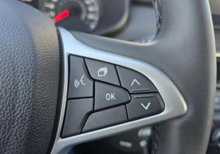 Gros plan sur les commandes multifonctions à gauche du volant noir du Dacia Sandero Stepway 2025.