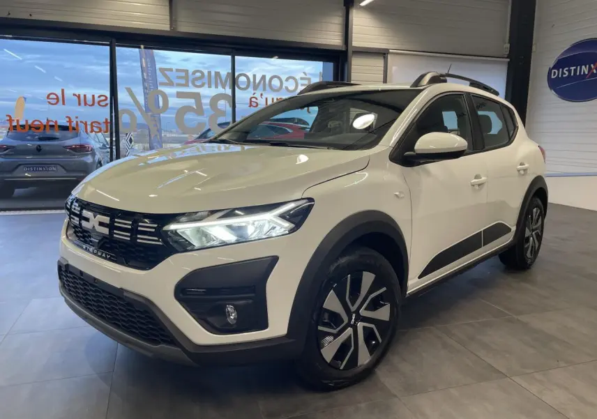 Vue 3/4 avant droit d'une Dacia Sandero Stepway 2025 blanc glacier avec calandre noire et jantes spécifiques.