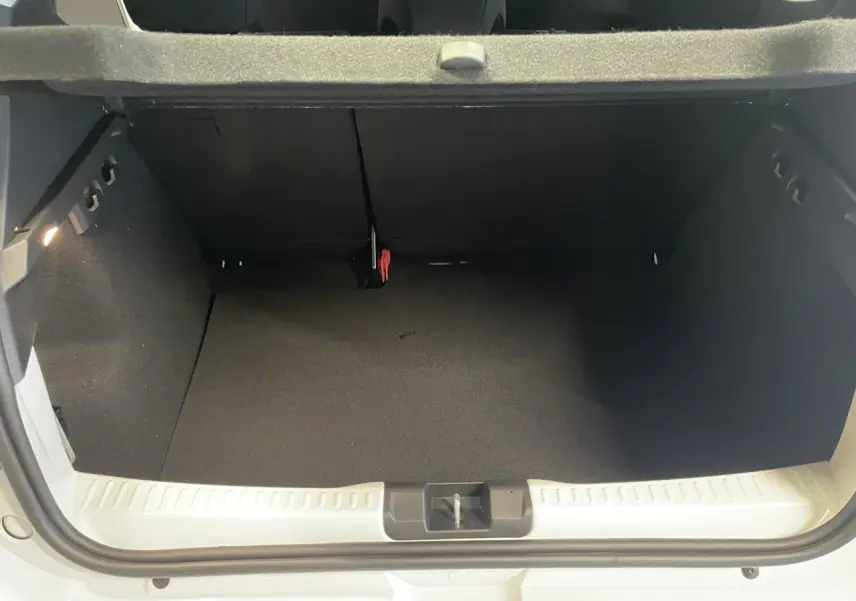 Coffre ouvert vu de l'arrière d'une Dacia Sandero Stepway blanc glacier, avec banquette arrière rabattable.