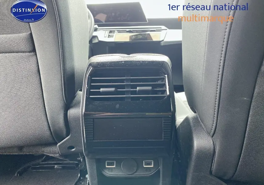Vue intérieure centrée sur la console arrière noire entre les sièges avant gris du Peugeot 5008 Hybrid 145 allure 2025.