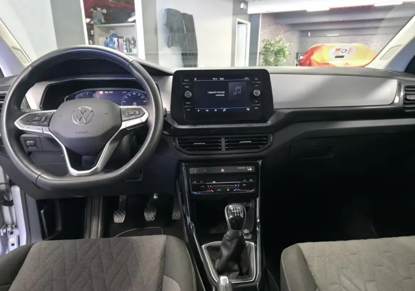 Vue intérieure frontale du Volkswagen T-Cross gris 2025, avec volant cuir multifonction et écran tactile central.