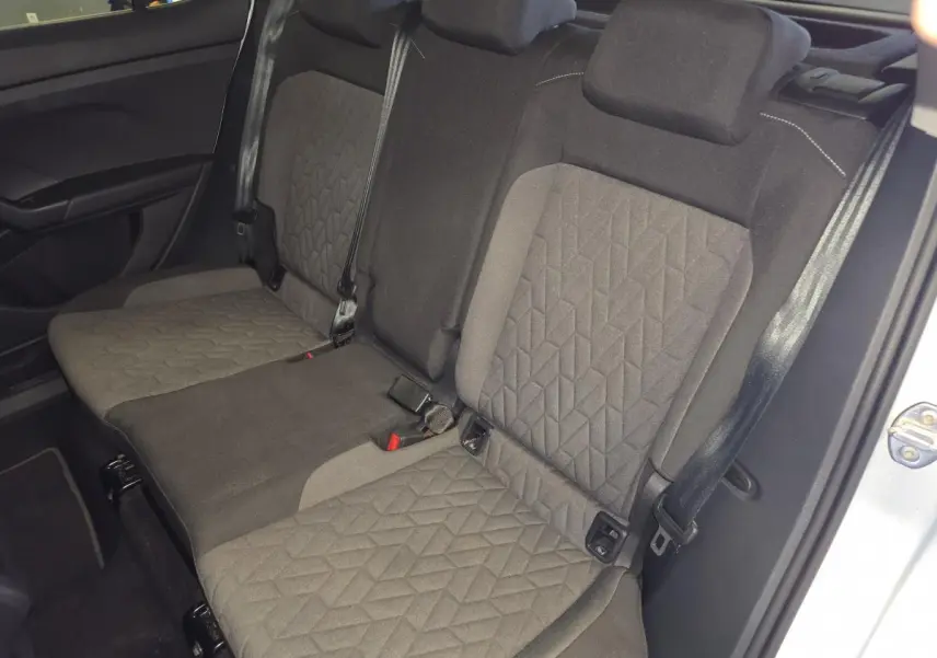 Vue intérieure de la banquette arrière en tissu gris du Volkswagen T-Cross 2025, avec ceintures de sécurité visibles.