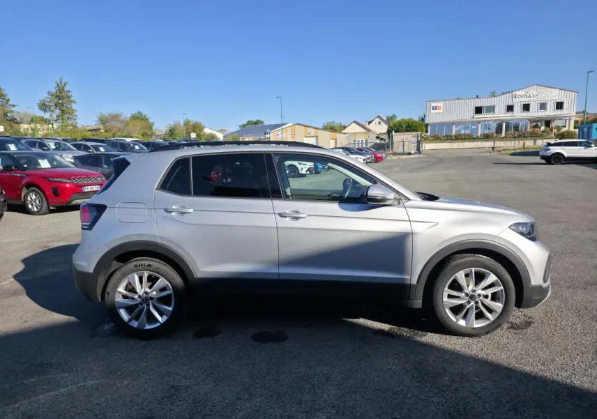 Vue latérale droite d'un Volkswagen T-Cross gris métallisé 2025 avec jantes alliage 17 pouces sur parking extérieur.