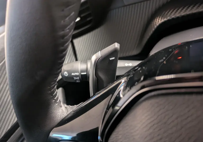 Gros plan sur la palette de changement de vitesse à gauche du volant cuir noir du Peugeot 2008 noir Perla 2024.