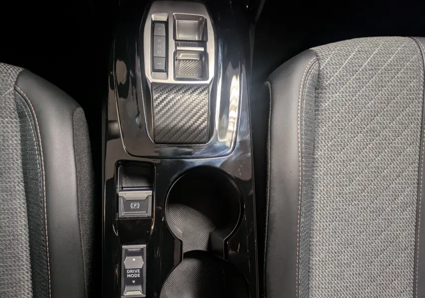 Vue plongeante sur la console centrale noire brillante du Peugeot 2008 1.2 130 EAT8 Allure, avec levier de vitesses et porte-gobelets.