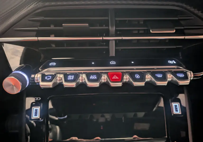 Gros plan sur la console centrale du Peugeot 2008 2024, boutons de commande éclairés et finition noire brillante.
