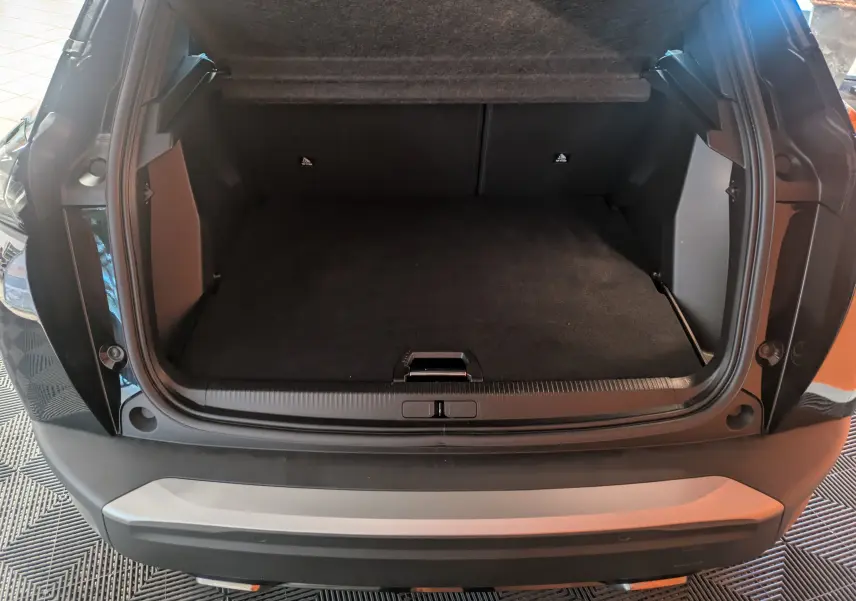 Coffre ouvert d’un Peugeot 2008 noir Perla 2024, vue arrière mettant en valeur l’espace de chargement vide.