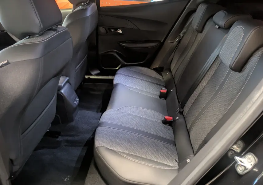 Vue intérieure arrière côté droit des sièges arrière en tissu et cuir du Peugeot 2008 noir Perla 2024, avec ceinture et appuie-têtes.