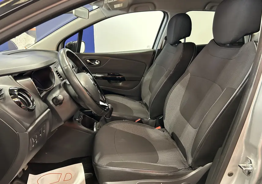 Intérieur avant du Renault Captur gris 2015, montrant les sièges tissu noirs et le tableau de bord côté gauche.