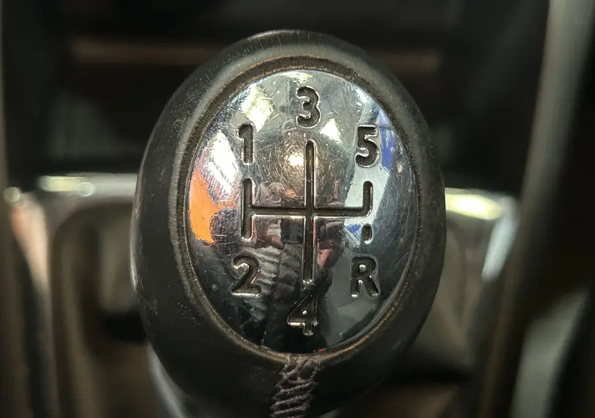 Gros plan sur le levier de vitesses manuel du Renault Captur gris, montrant les positions des 5 rapports et de la marche arrière.
