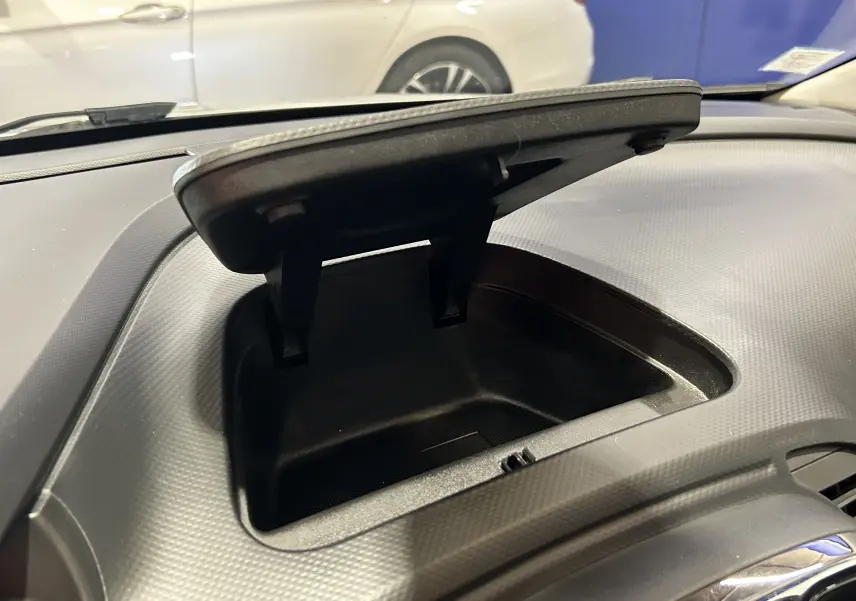 Rangement ouvert sur le tableau de bord d’un Renault Captur gris, vue intérieure centrée sur la console avant.