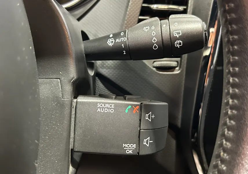 Gros plan sur les commandes audio au volant du Renault Captur dCi 90ch gris, montrant les boutons de volume et source audio.