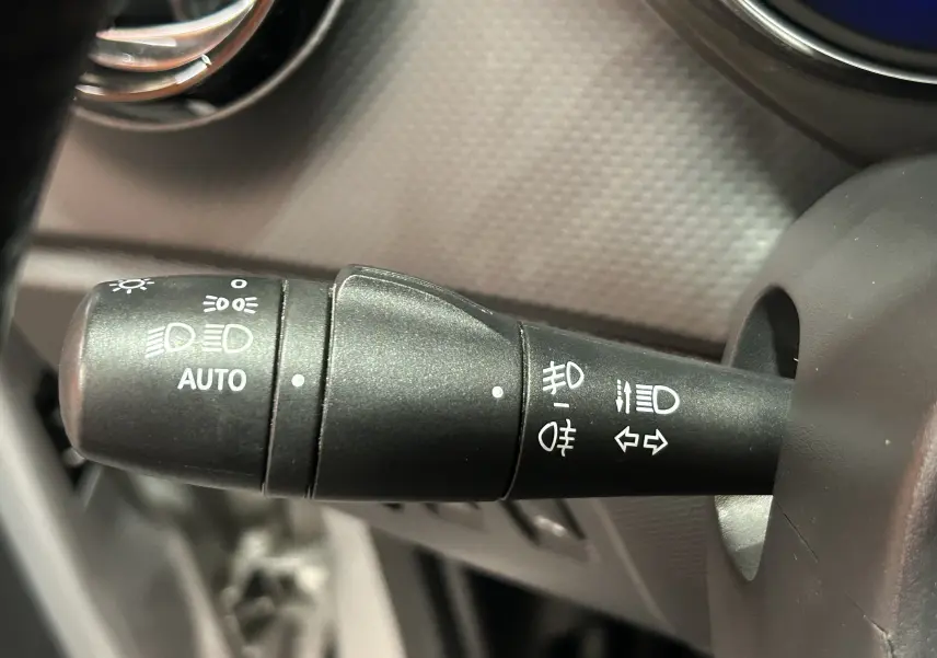 Gros plan sur la manette de commande des phares et clignotants du Renault Captur gris, avec réglage automatique des feux.