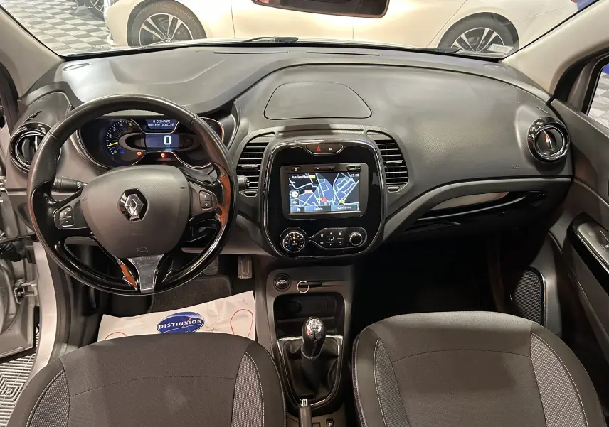 Intérieur du Renault Captur gris 2015, vue frontale du tableau de bord avec écran GPS et volant multifonction.