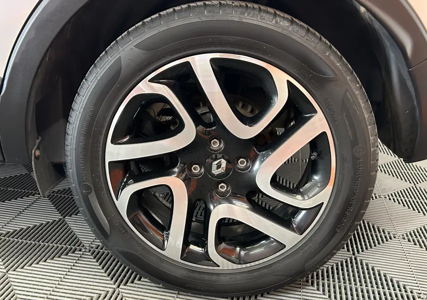 Gros plan sur la jante alliage bicolore noire et argent du Renault Captur gris, avec logo Renault au centre.