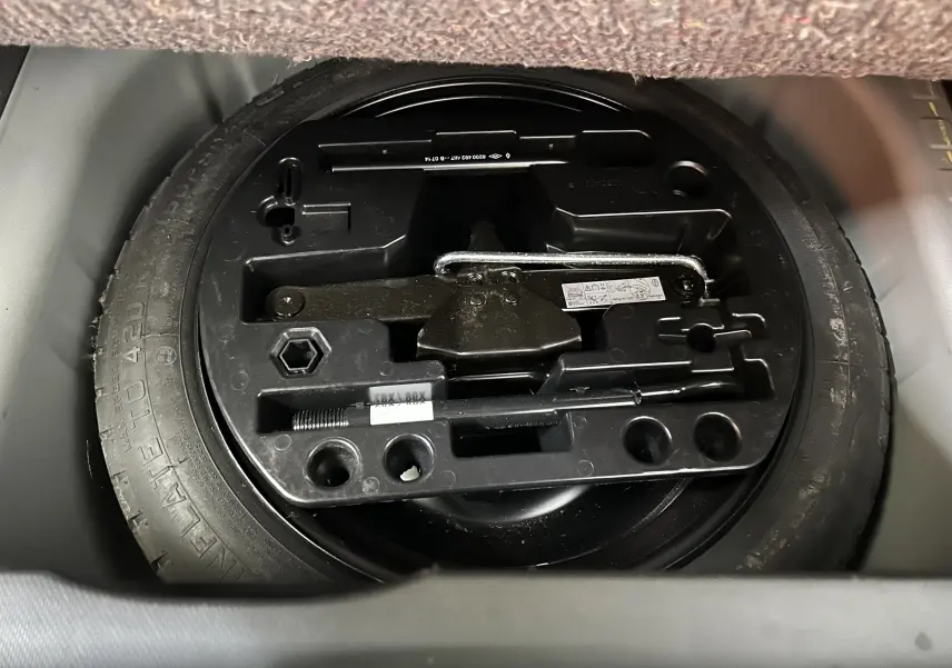 Gros plan sur la roue de secours et le kit d'outils dans le coffre du Renault Captur gris dCi 90ch energy Intens 2015.