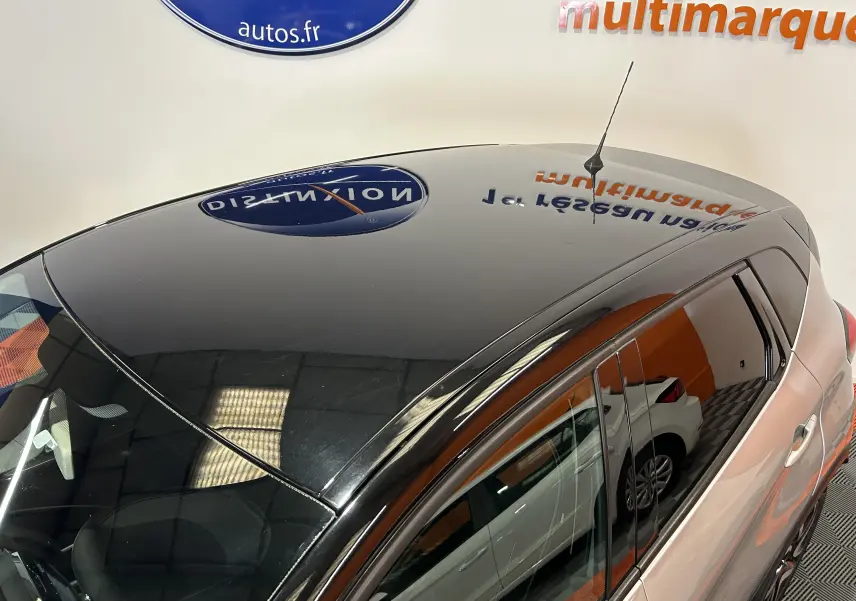 Vue en plongée du toit noir brillant et côté droit gris du Renault Captur dCi 90ch energy Intens avec antenne et vitres teintées.