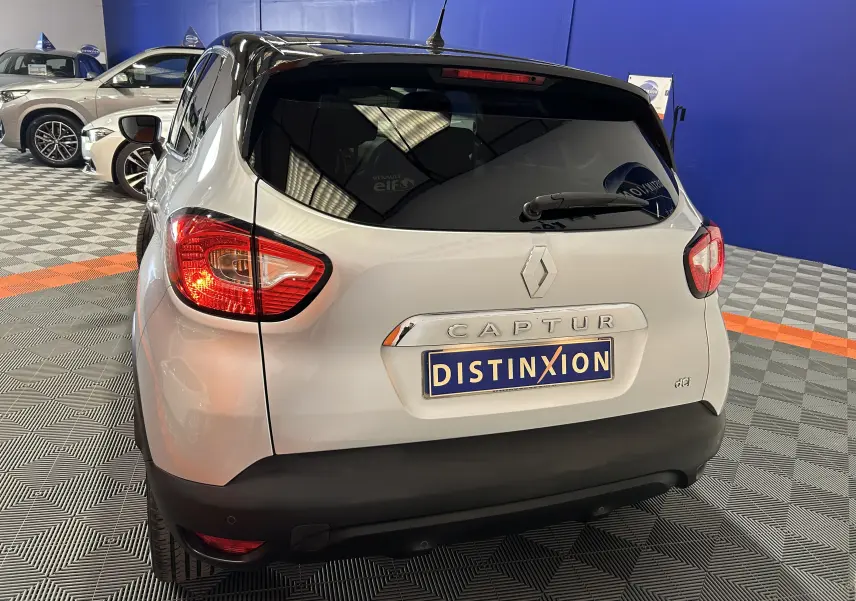 Vue arrière d'un Renault Captur gris 2015 avec feux allumés et plaque Distinxion dans un showroom.
