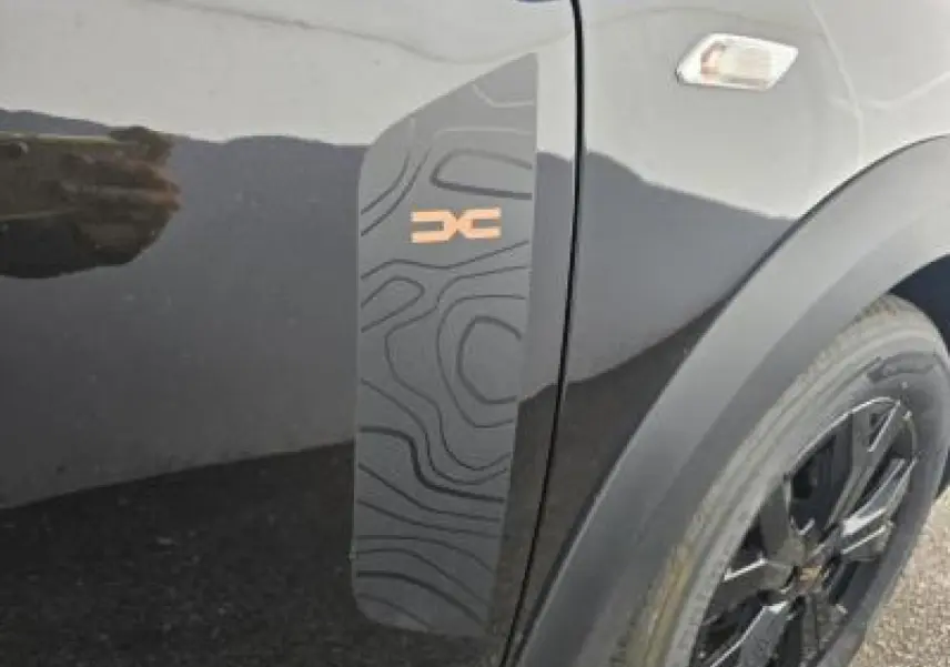 Détail du sticker topographique noir avec logo Stepway brun sur la porte côté avant droit d'une Dacia Sandero III Stepway noir nacré.