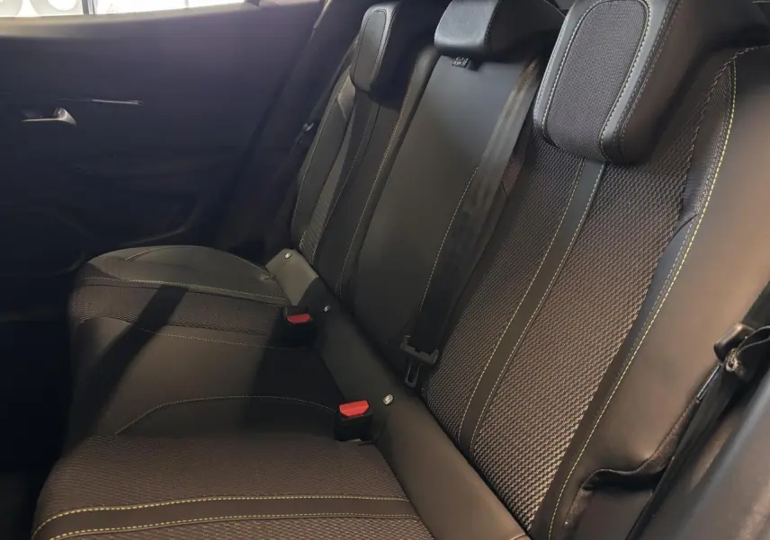 Vue rapprochée des sièges arrière noirs avec surpiqûres vertes du Peugeot 2008 hybride 2025.