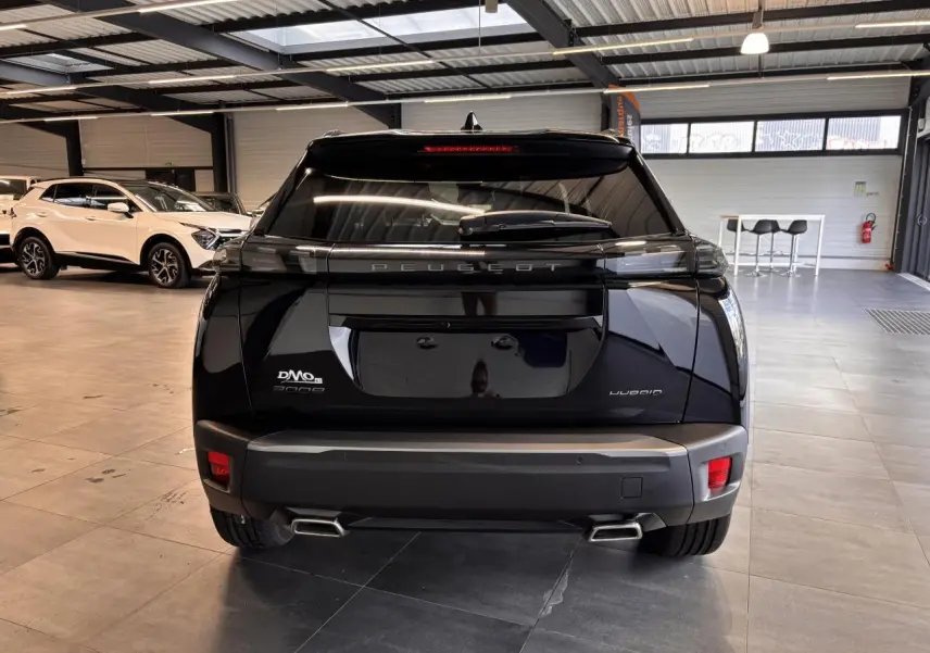 Vue arrière d'un Peugeot 2008 noir hybride 2025 en showroom avec double sortie d'échappement chromée.