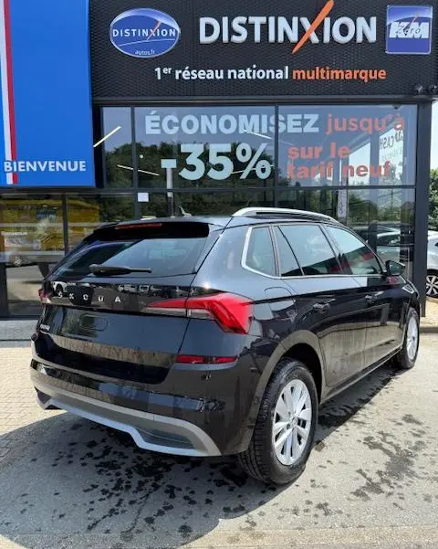 Vue 3/4 arrière droite d'un Skoda Kamiq noir 2024 garé devant une vitrine avec enseigne Distinxion.