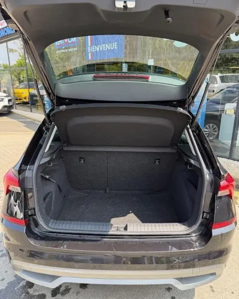 Vue arrière du coffre ouvert d'un Skoda Kamiq noir 2024, montrant l'espace de chargement et la tablette de séparation.