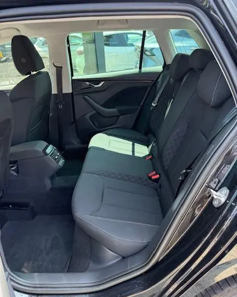 Vue intérieure côté droit de la banquette arrière noire du Skoda Kamiq 2024 avec finitions tissu et ceinture de sécurité rouge.