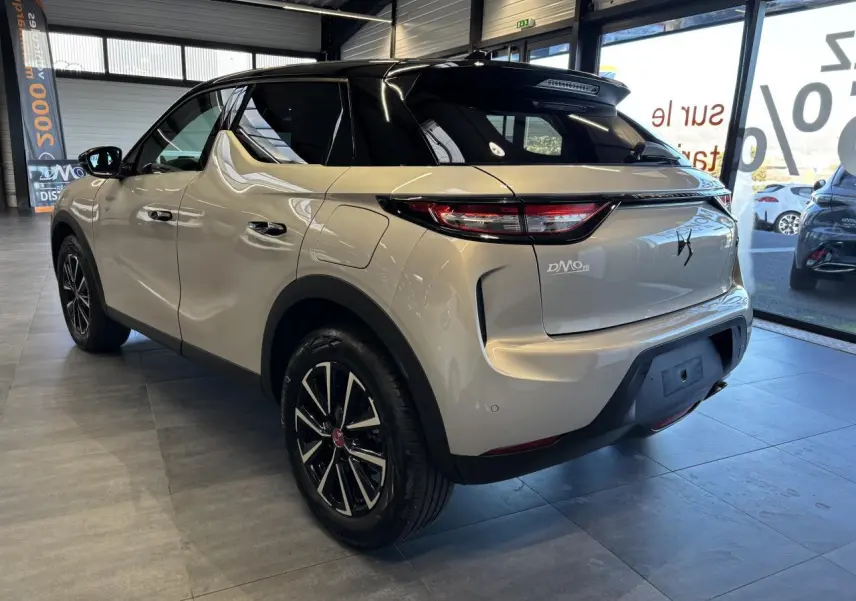 Vue 3/4 arrière droite du DS3 Crossback 2024 en couleur Crystal Pearl avec toit noir et jantes noires en concession.