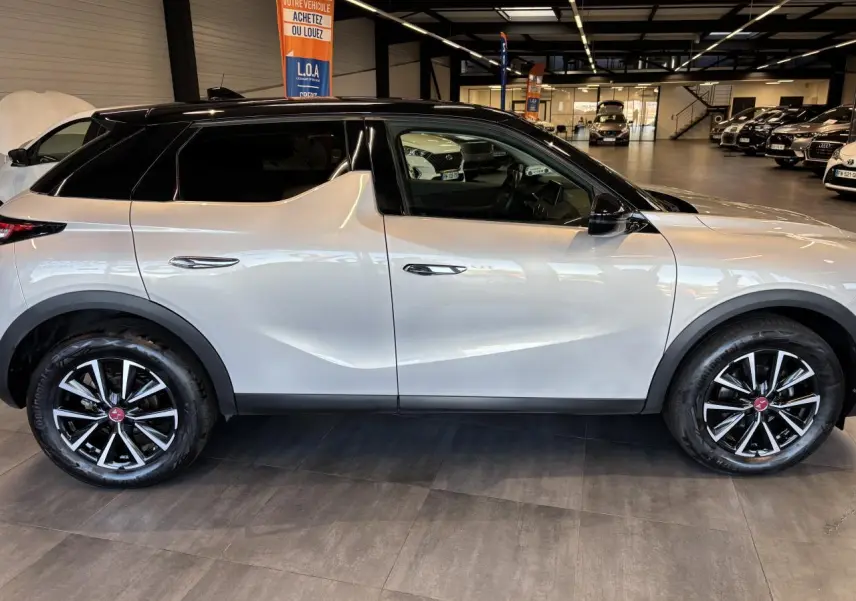 Vue de profil côté gauche du DS3 Crossback 2024 en Crystal Pearl, avec toit noir et jantes noires à détails argentés.