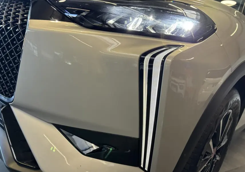 Gros plan sur l'avant droit du DS3 Crossback 2024 en Crystal Pearl, mettant en valeur ses feux LED verticaux et la calandre distinctive.