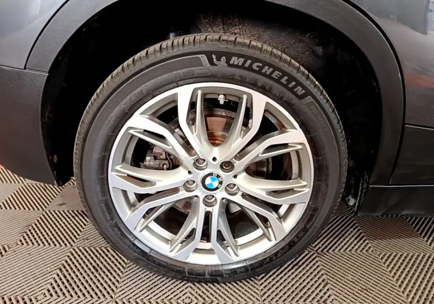 Gros plan sur la roue avant droite avec jante alliage argentée du BMW X2 hybride rechargeable couleur gris foncé.