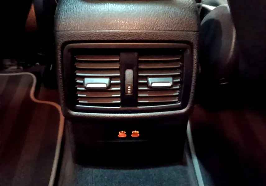 Gros plan sur la console centrale arrière noire du BMW X2 xDrive25e avec aérateurs et voyants chauffants allumés.