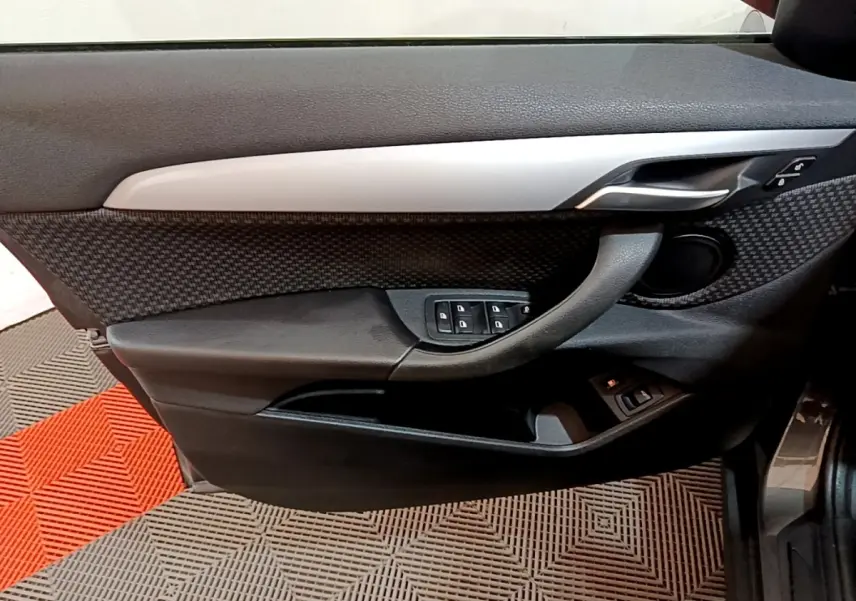 Vue rapprochée de la porte avant gauche de la BMW X2 hybride rechargeable, avec garniture noire et insert gris métallique.