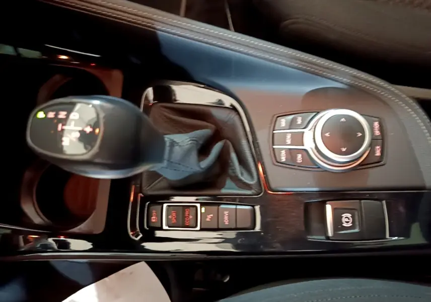 Vue rapprochée de la console centrale noire du BMW X2 xDrive25e 2020, avec levier de vitesse automatique et commandes multimédia.