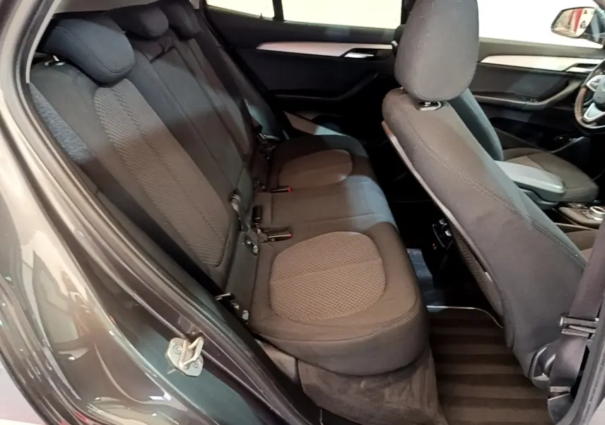 Vue intérieure côté gauche montrant les sièges arrière noirs et le dossier du siège avant d'une BMW X2 hybride rechargeable.