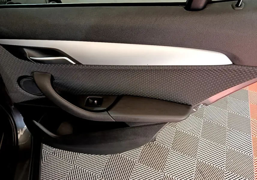 Gros plan sur la porte intérieure côté gauche de la BMW X2 hybride rechargeable, avec poignée noire et insert argenté.