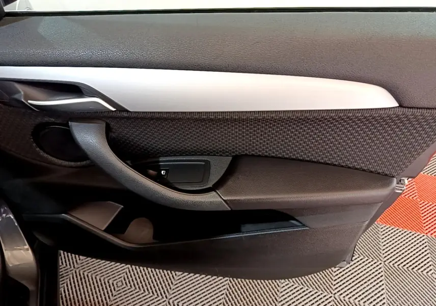 Vue intérieure côté gauche de la porte BMW X2 xDrive25e avec garniture noire et insert argenté.