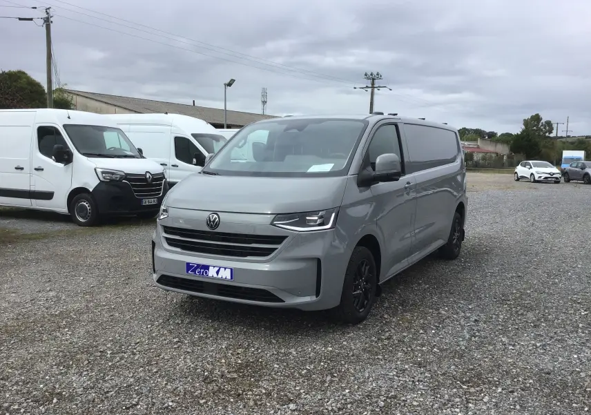 Volkswagen Transporter T7 gris Stone vu en 3/4 avant droit avec projecteurs LED Matrix et barres de toit repliables.