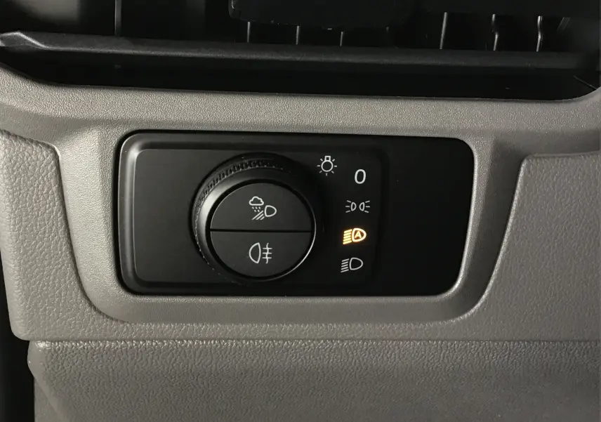 Gros plan sur la commande d'éclairage du Volkswagen Transporter T7 gris stone, avec témoin de feux automatiques allumé.